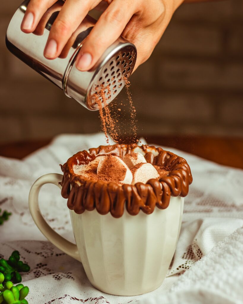 a hand pouring cocoa on a cup of coffee