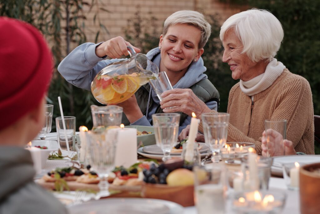 a woman pouring lemonade into a glass of an old woman