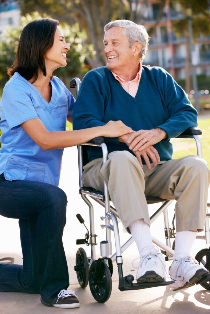 an old man on wheelchair smiling at the caregiver
