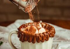a hand pouring cocoa on a cup of coffee