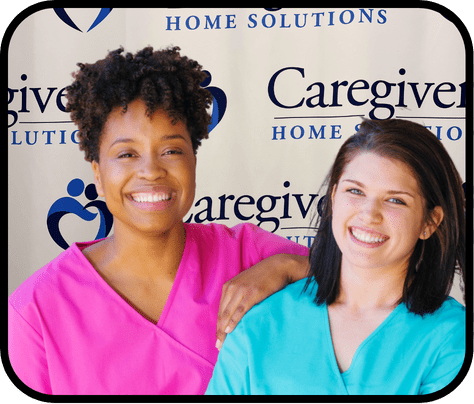 Two smiling caregivers in colorful uniforms.